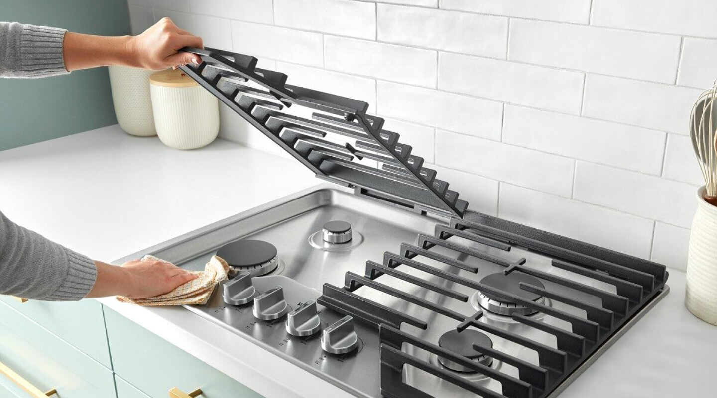 Person lifting the grate on a gas cooktop