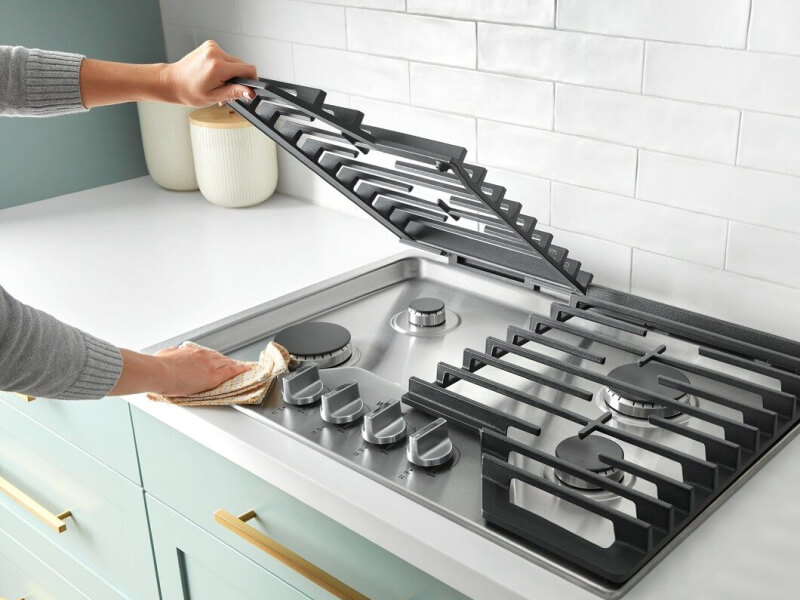 Person lifting the grate on a gas cooktop