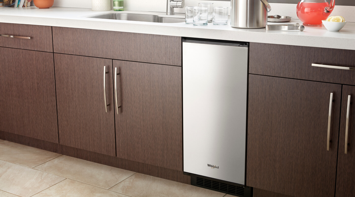 A Whirlpool® Icemaker installed amid brown cabinetry