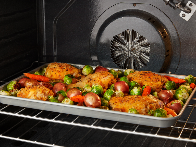 Chicken and vegetables roasting in a convection oven