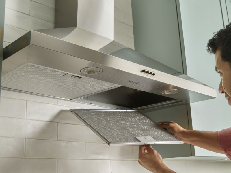 A person changing the filter on a range hood.