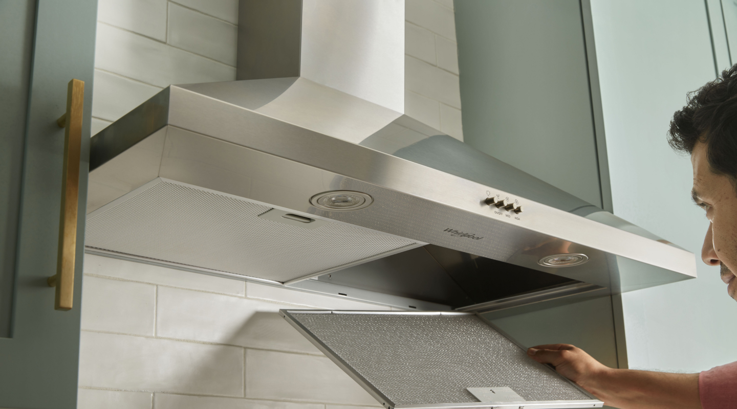 A person changing the filter on a range hood.