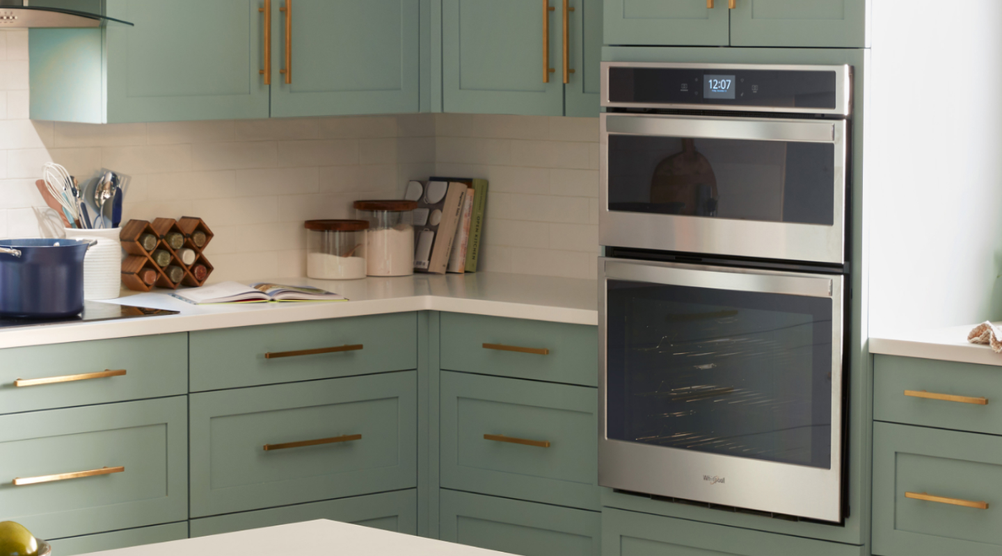 A double wall oven in a kitchen with green cabinetry
