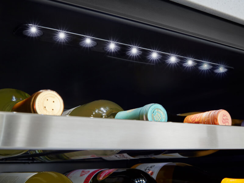 Up close image of wine bottles in an undercounter fridge
