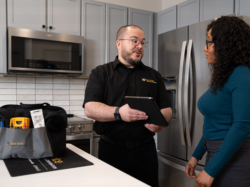A technician helping a woman in her kitchen