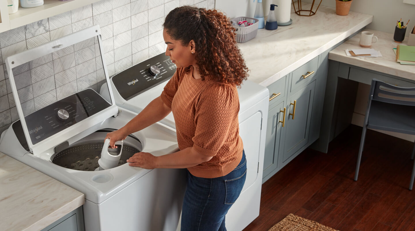 A person adjusting a removable agitator in their Whirlpool® Washer