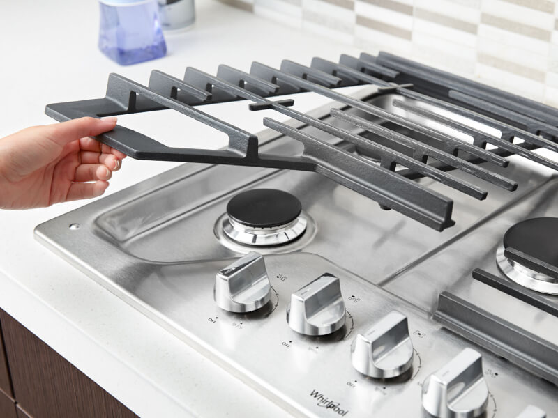 Person placing grates back on a gas cooktop