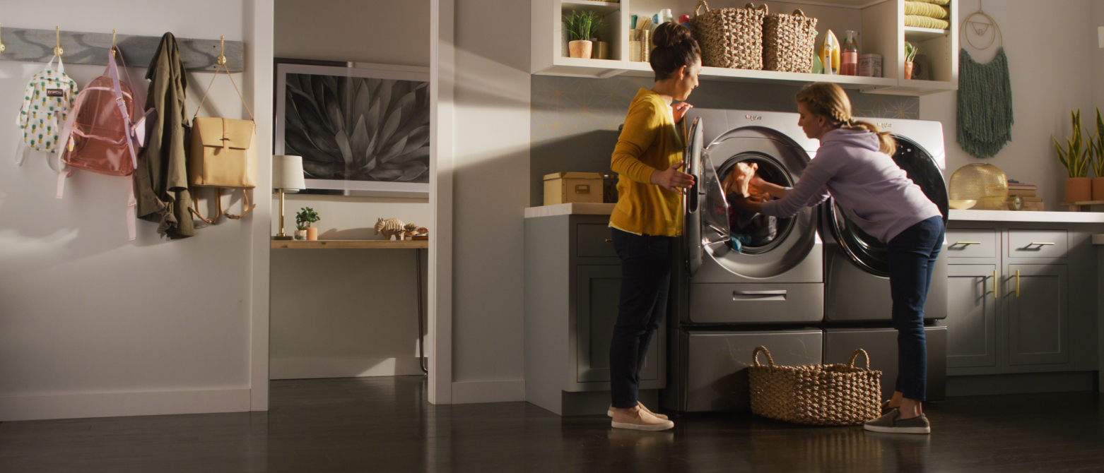 Two women unload laundry from a front load washer