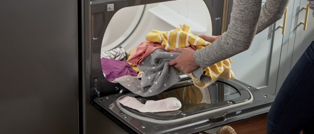 A person removing clothes from a dryer