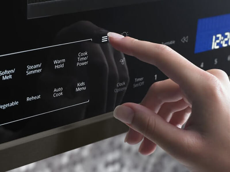 Hand pressing buttons on microwave control panel