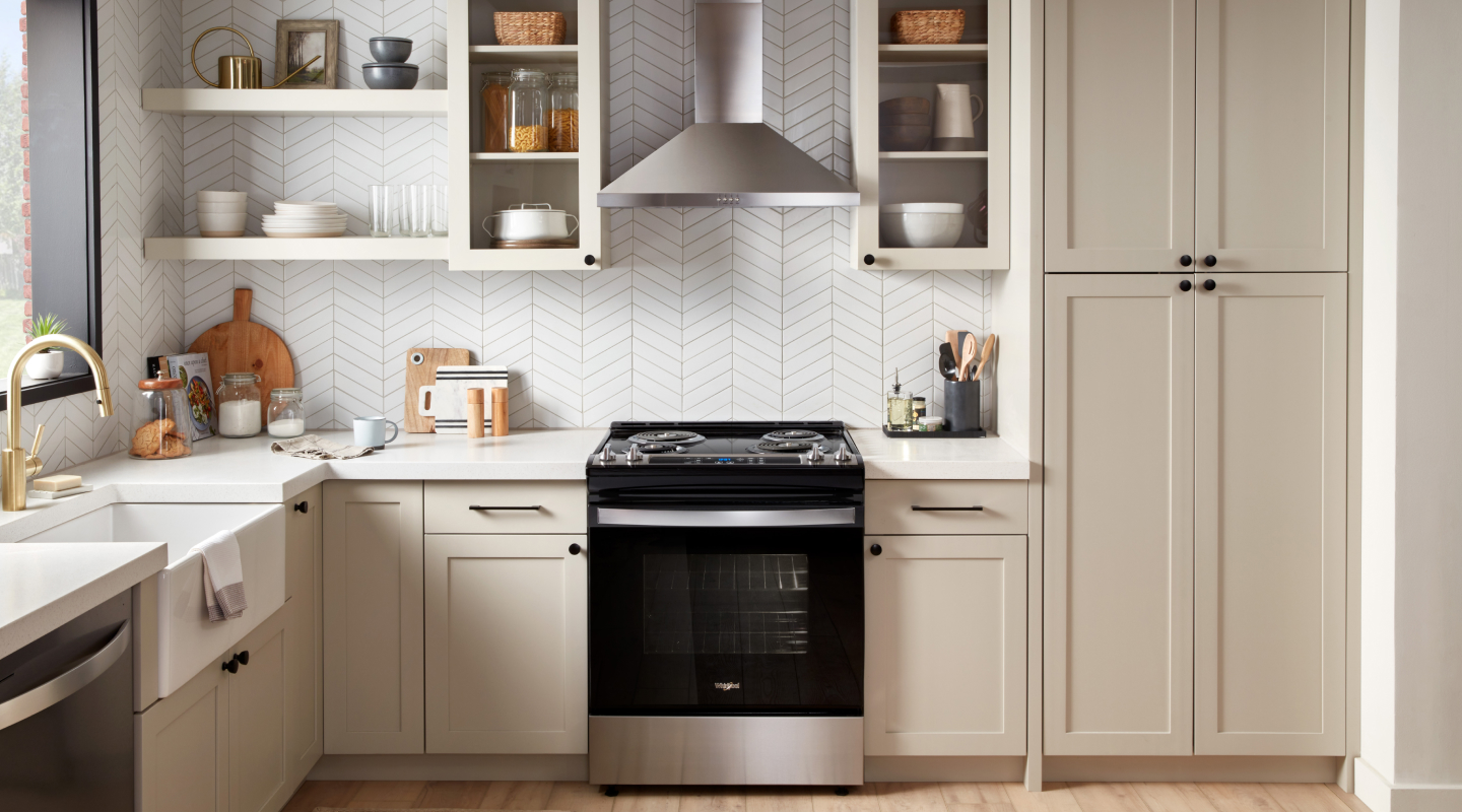A stainless steel range hood above a black range