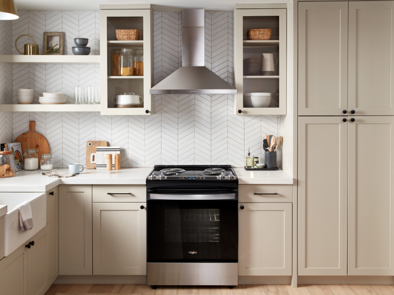 A stainless steel range hood above a black range