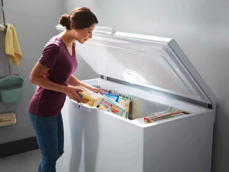 Person placing food in garage-ready chest freezer