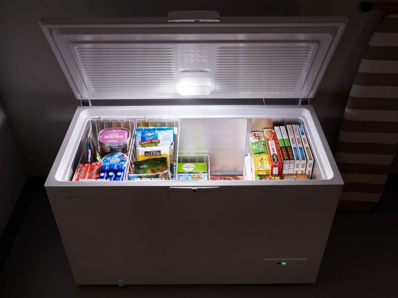 Chest freezer with food inside opened with light on