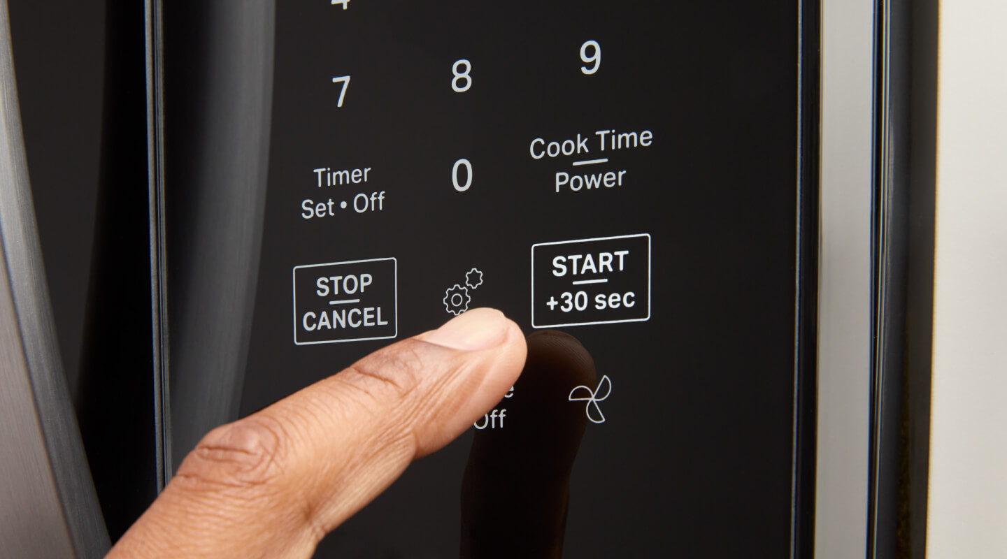 Person selecting settings on a microwave keypad