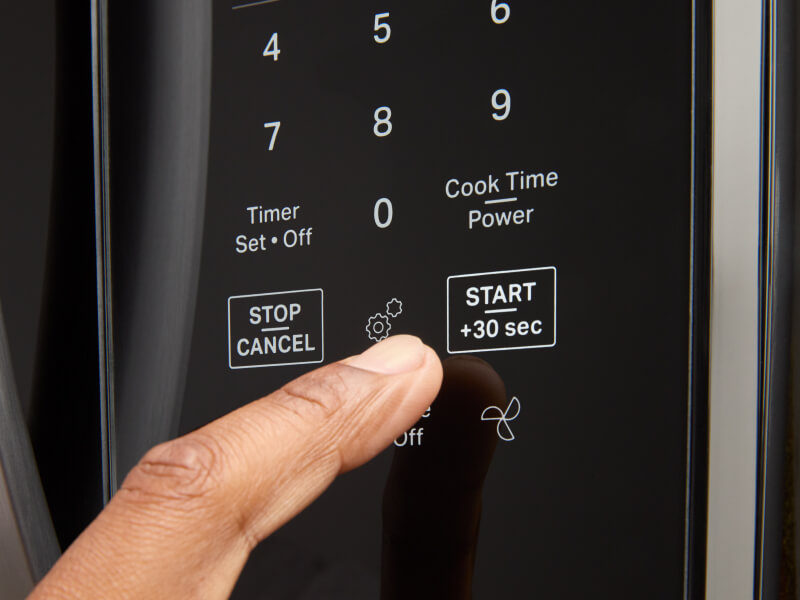 Person selecting settings on a microwave keypad