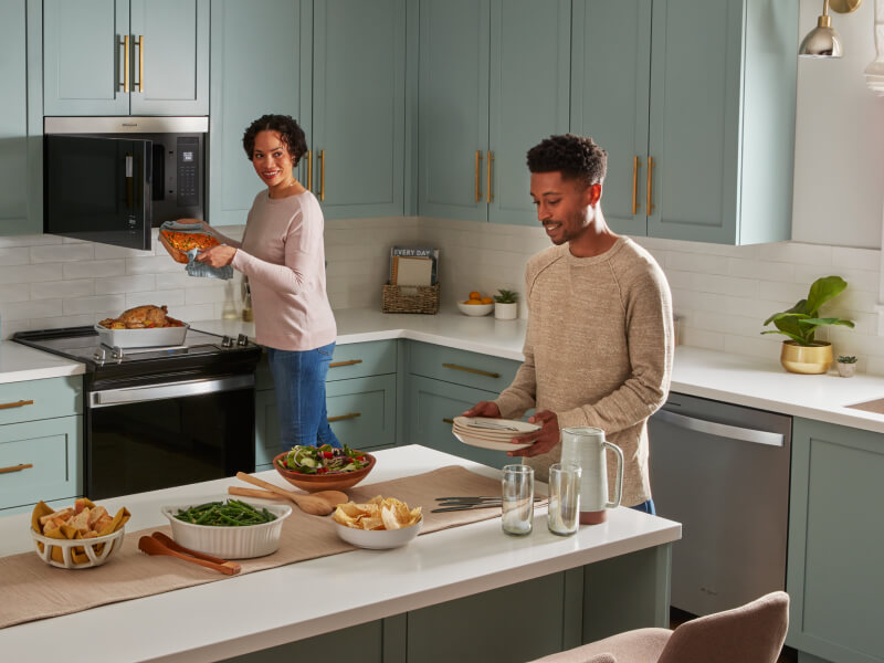 People preparing food in an open kitchen with blue cabinetry 