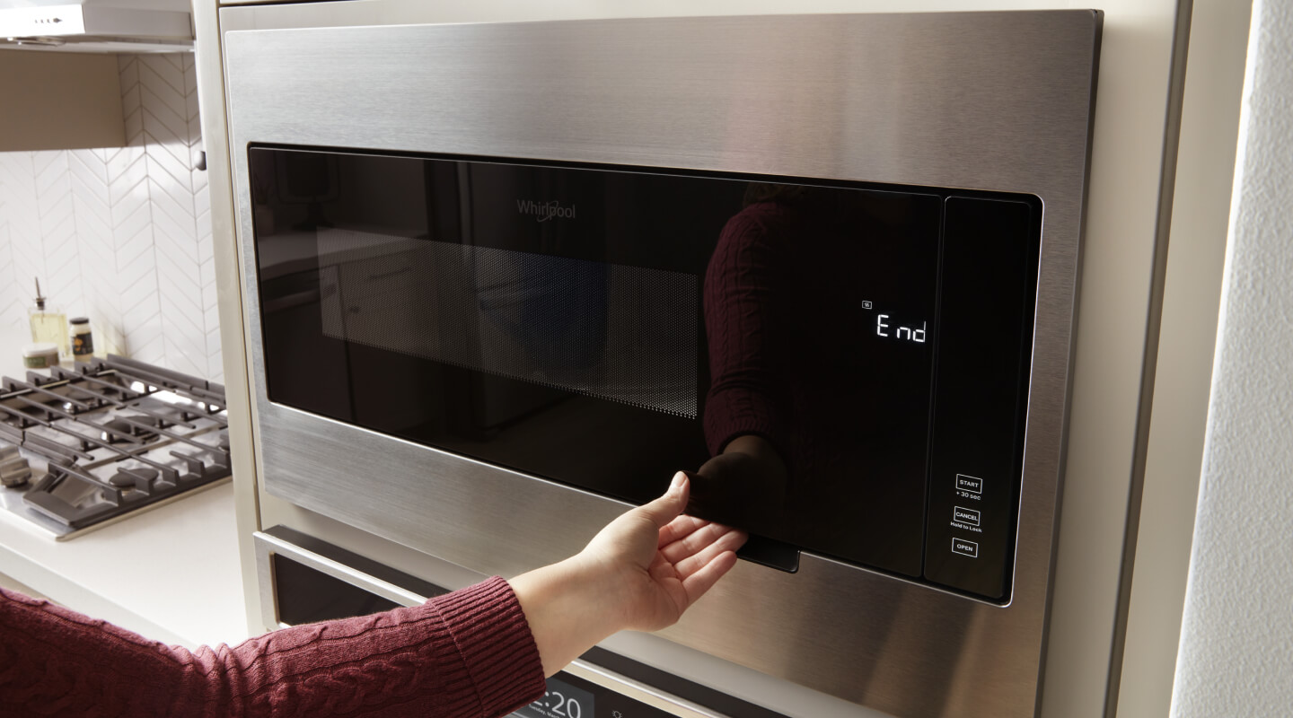 Hand opening a microwave door
