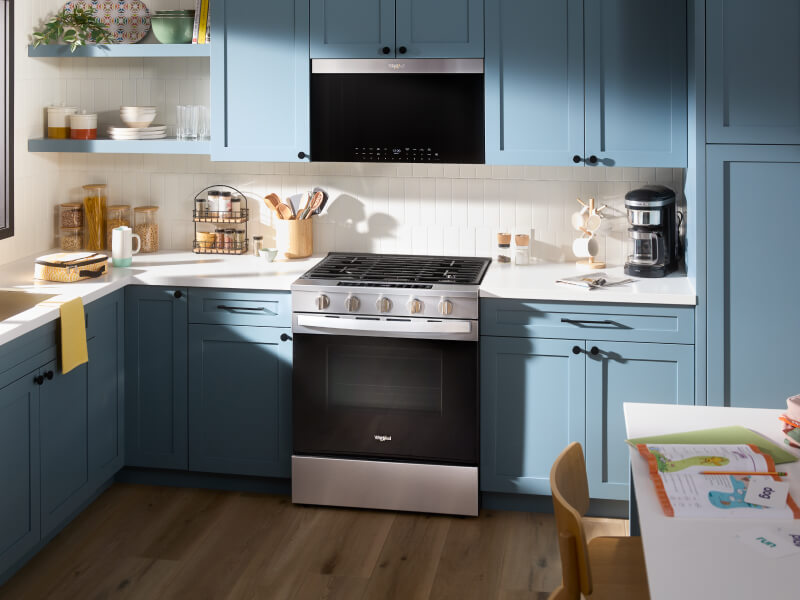 Kitchen with blue cabinetry and stainless steel Whirlpool® appliances
