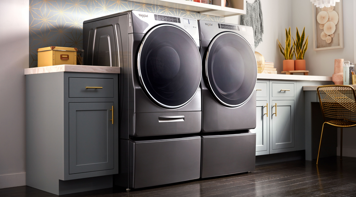 A gray front load Whirlpool® washer and dryer set in a modern laundry room