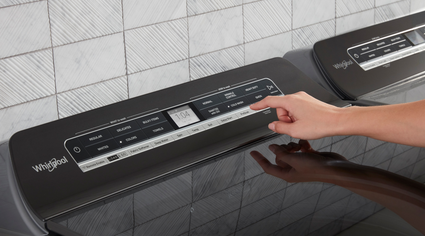 A person selects a laundry cycle from a touchpad
