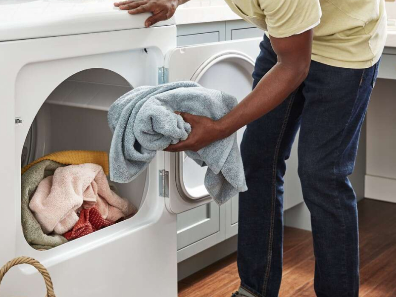 Person removing a towel from a Whirlpool brand dryer