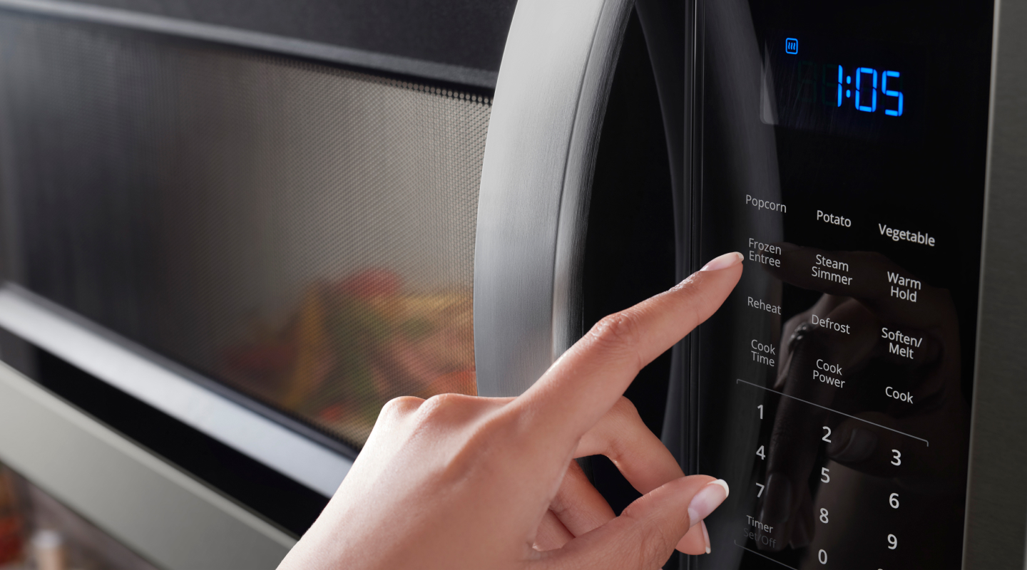 Person pressing button on a Whirlpool® microwave