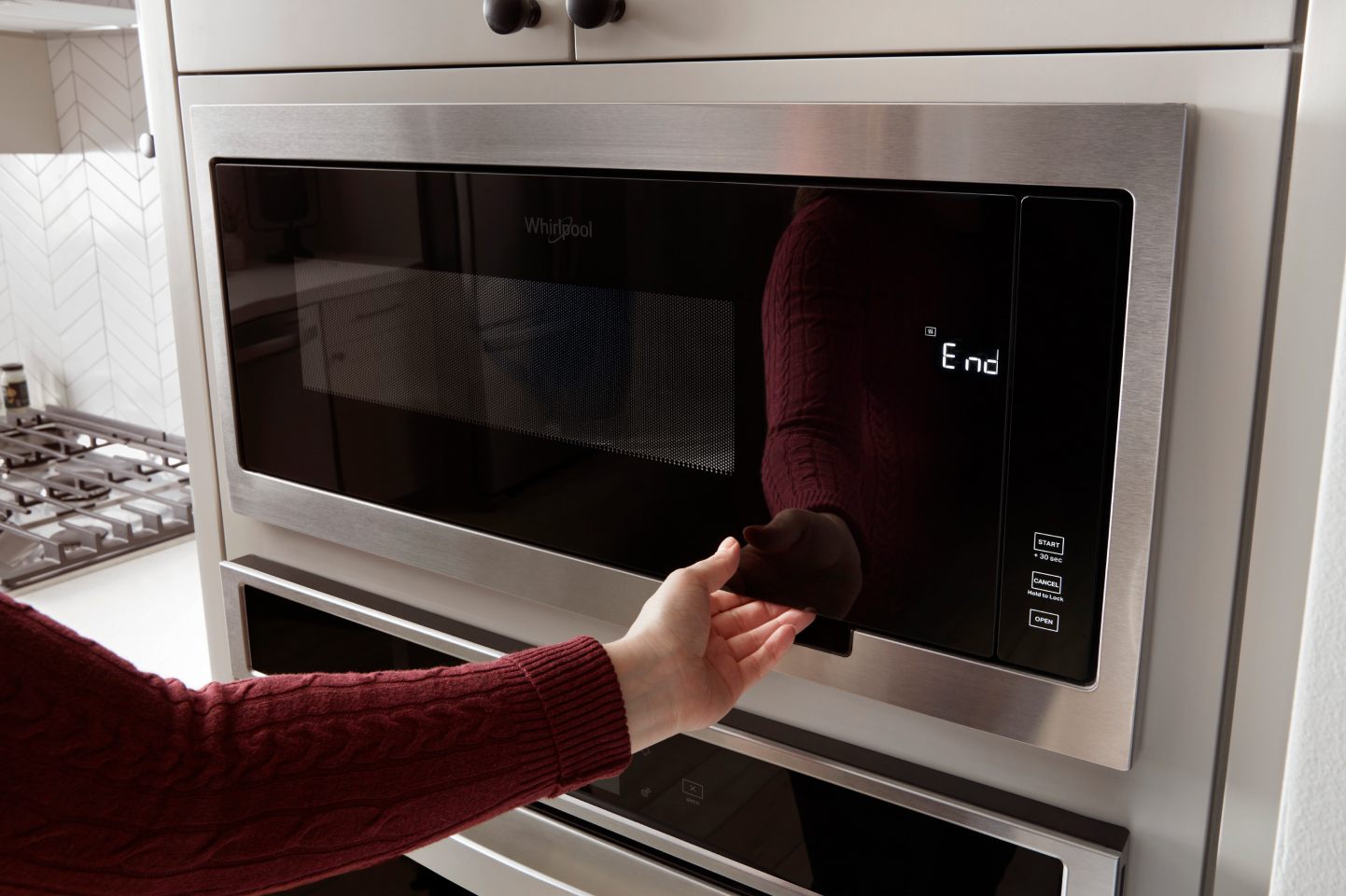 A hand opening a Whirlpool microwave