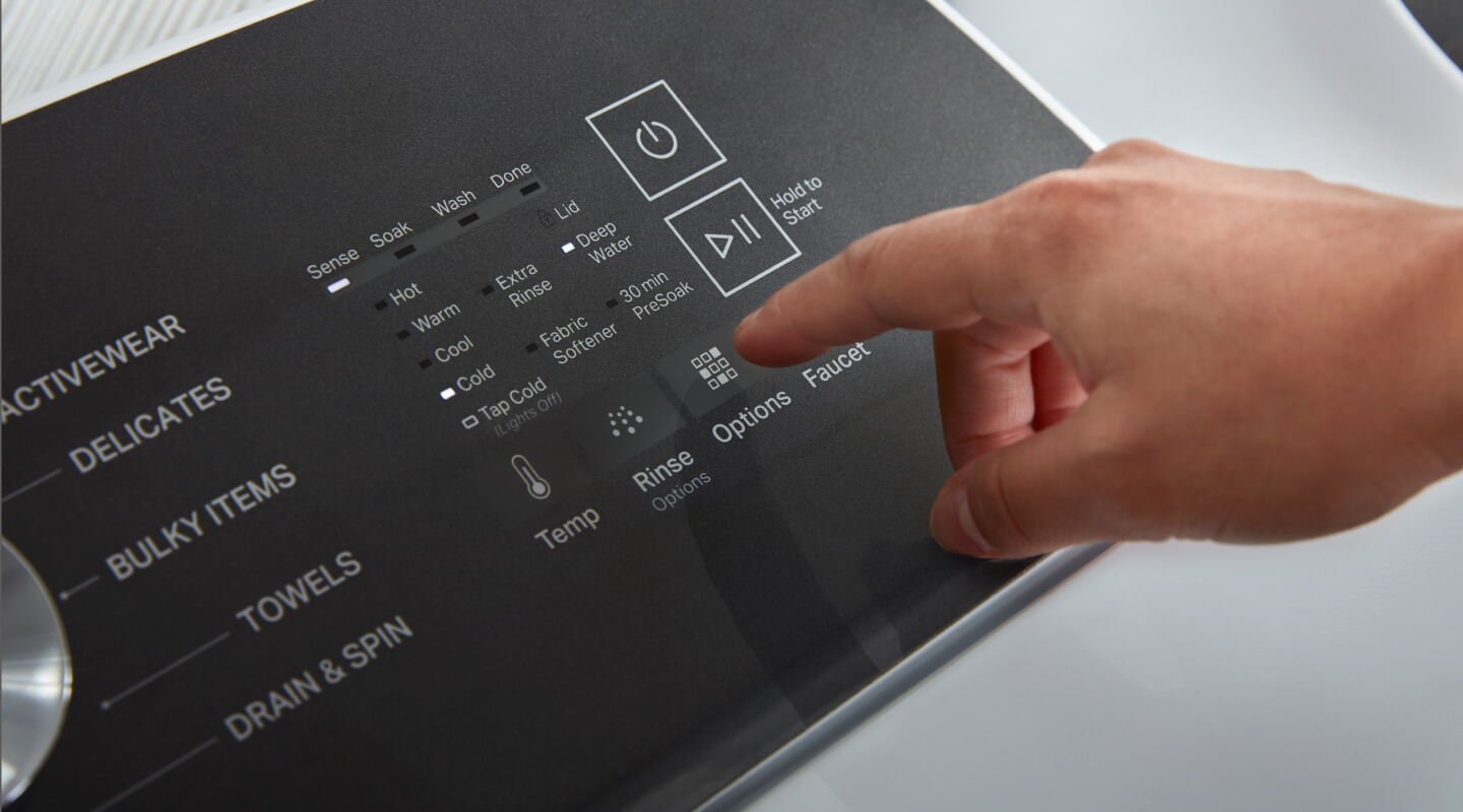 A hand selecting cycle settings on a washing machine control panel