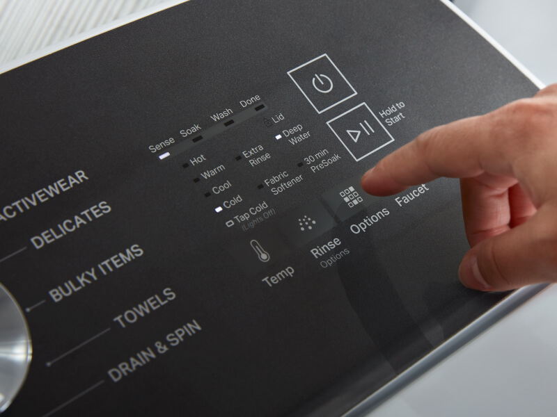 A hand selecting cycle settings on a washing machine control panel