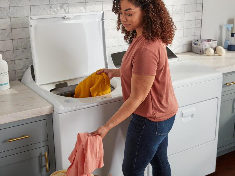 Person removing clothes from a top load washing machine