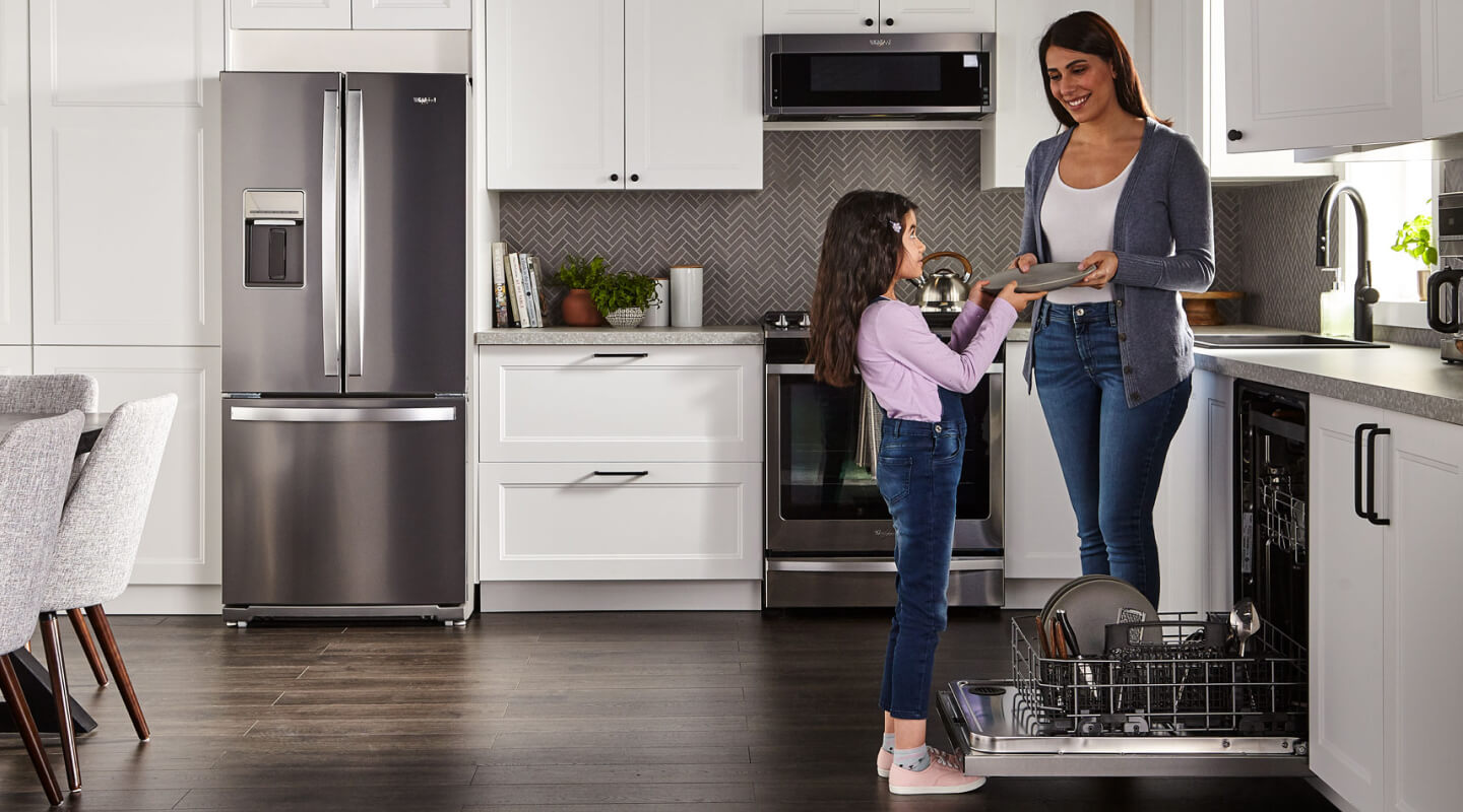Person handing a child a clean dish next to a dishwasher