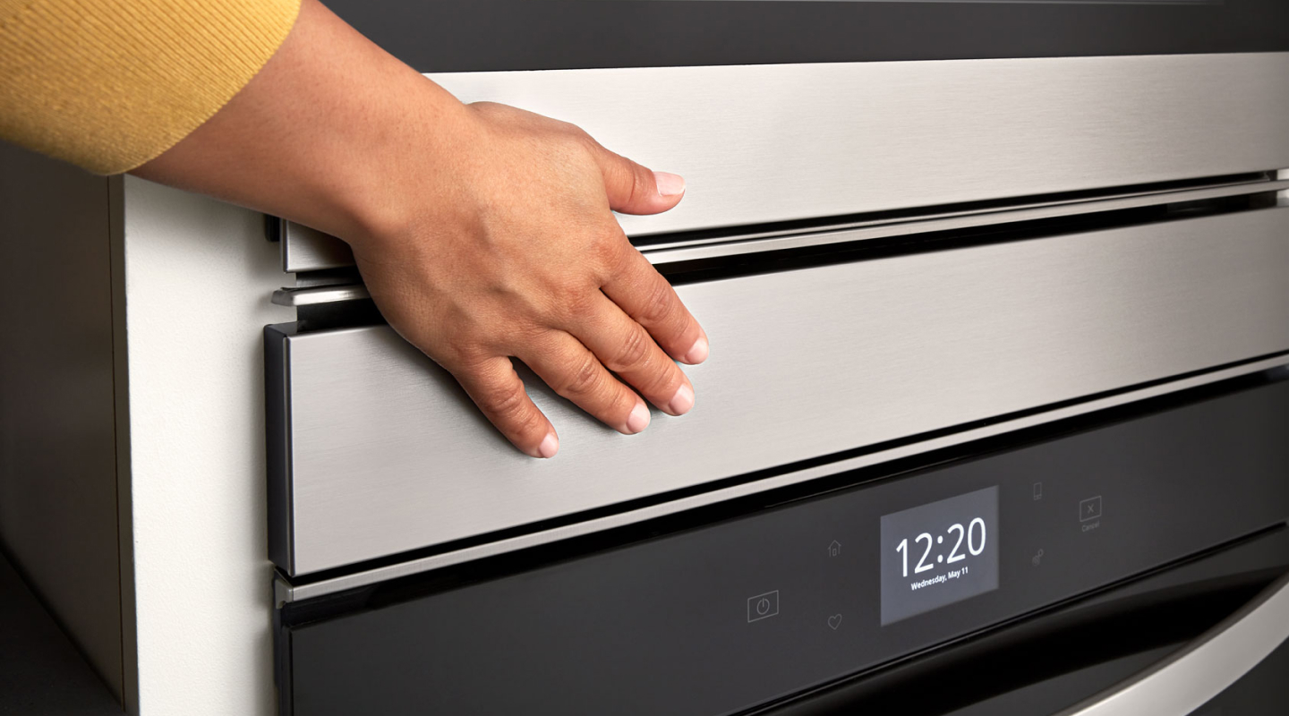 Person’s hand over an oven door above a digital display