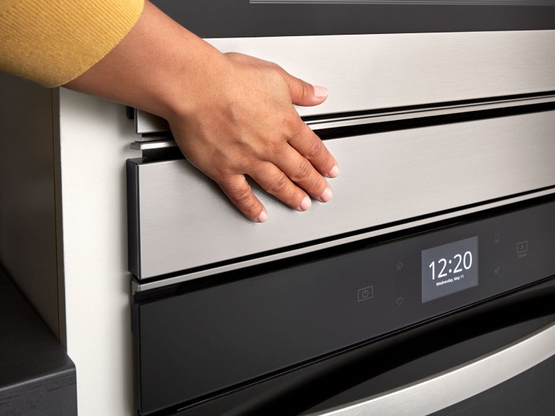 Person’s hand over an oven door above a digital display