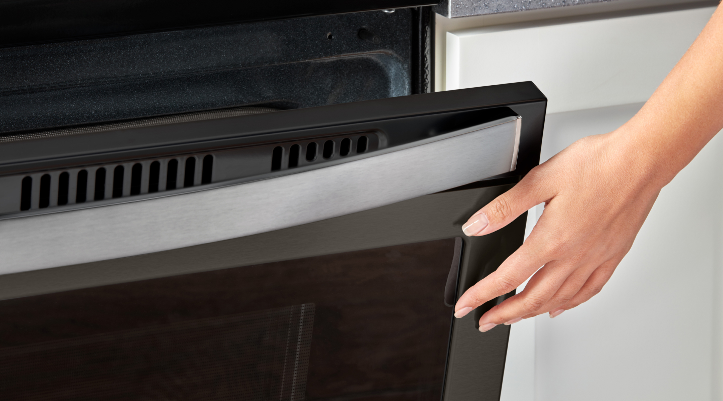 Person closing a slightly opened oven door