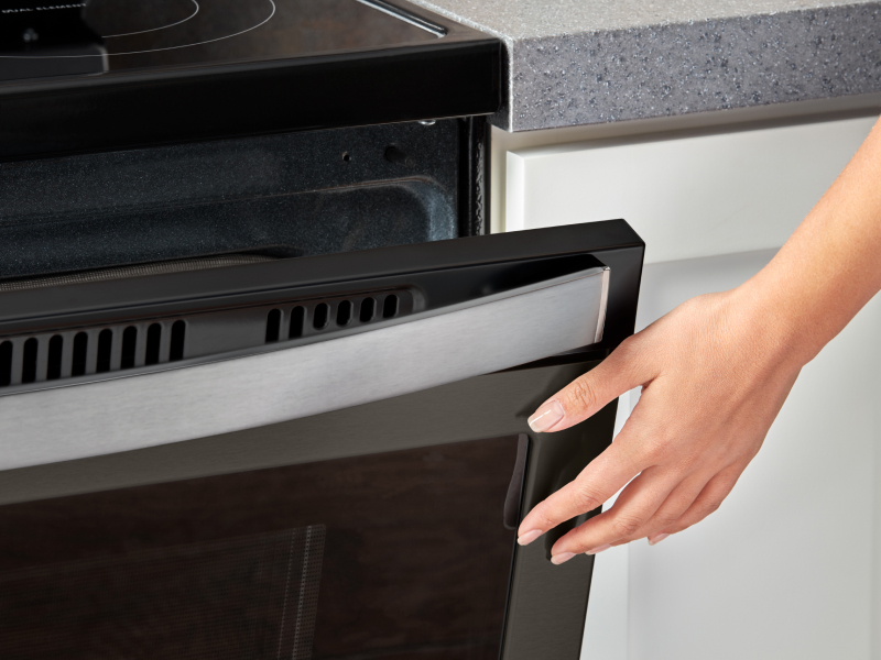 Person closing a slightly opened oven door