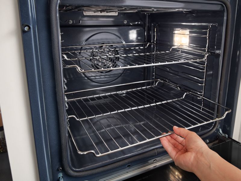 Hand removing racks from inside oven