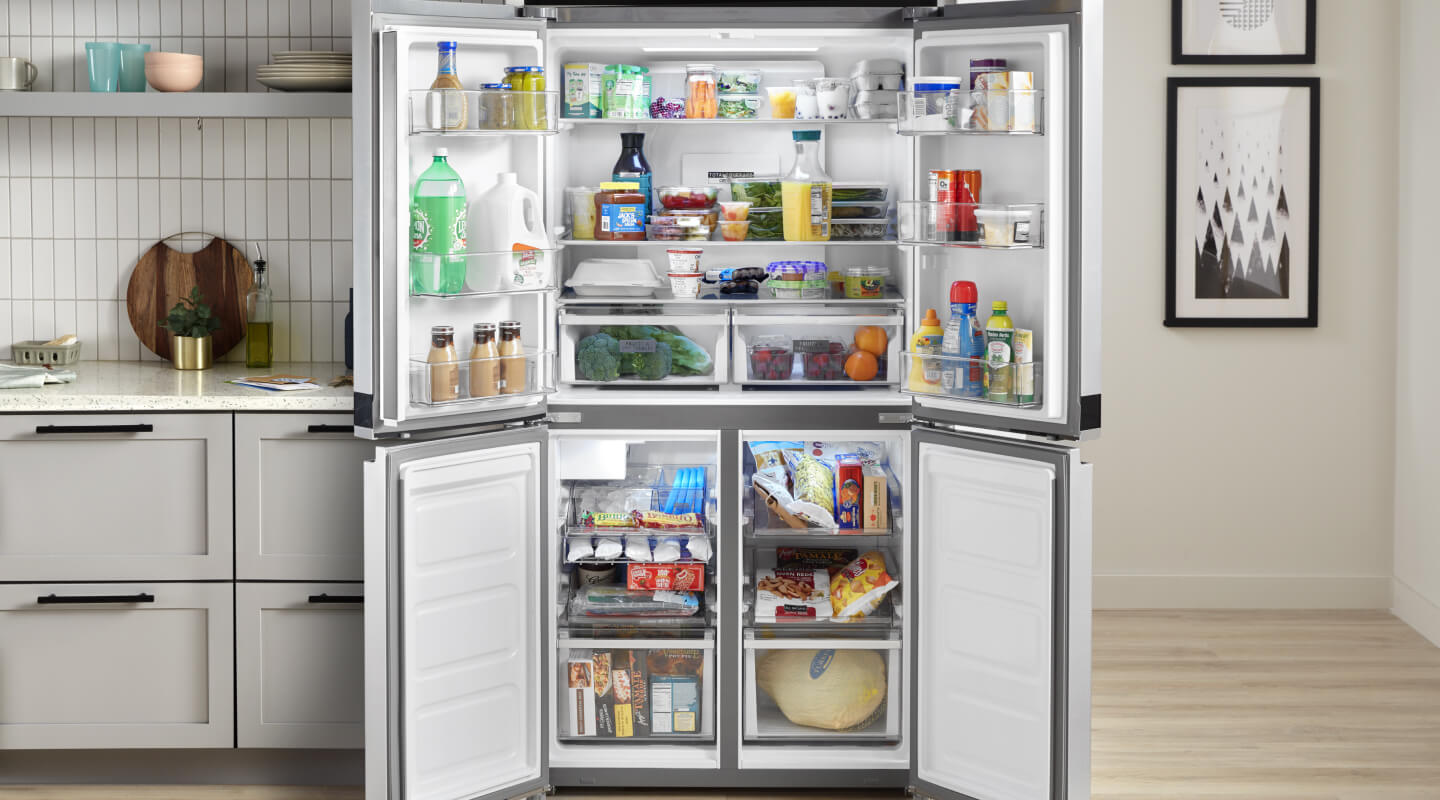 An all-white kitchen with an open refrigerator in it