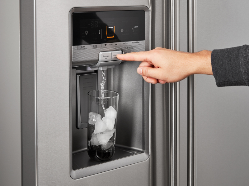 A person dispensing water out of a refrigerator ice maker