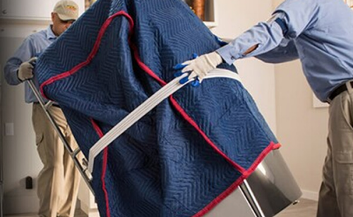 Person moving large appliance covered in a moving blanket with a hand truck