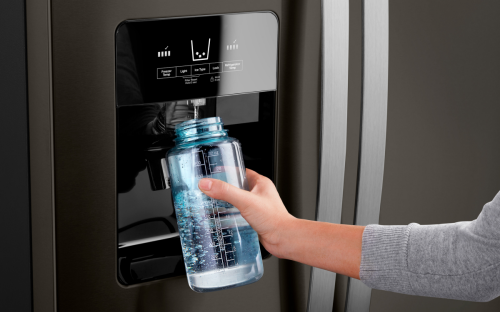 A person filling up their water bottle from the fridge