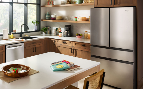 Pulled back view of a kitchen with stainless steel appliances including a refrigerator