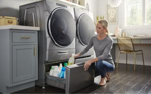 Person organizing cleaners inside a laundry machine pedestal