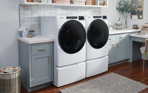 Laundry room with a white Whirlpool® front load laundry pair in blue cabinets and white counters