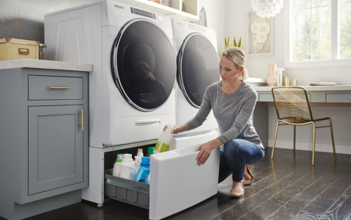 Person placing cleaner in pedestal storage beneath laundry unit