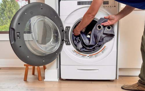 Someone putting curtains into a front load washer