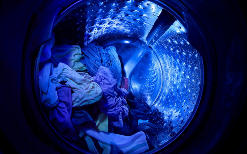 Blue light from UV Clean Technology in a Whirlpool® Washer shining in a wash basket