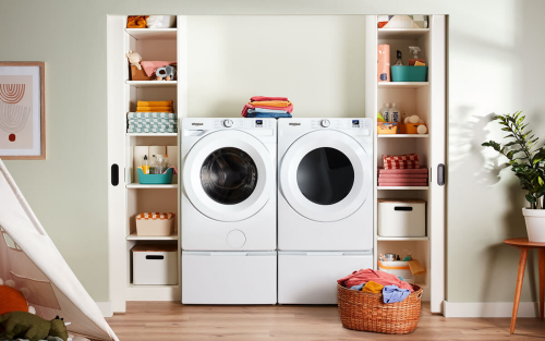 A white Whirlpool® Front Load Washer and Dryer on top of pedestals and inside a wide laundry closet with shelves on each side