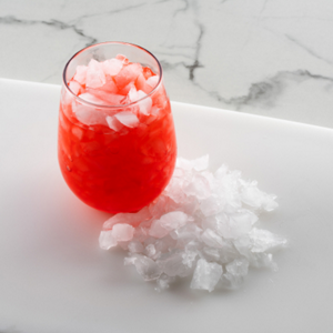 Crushed ice on tray and in a glass with red beverage